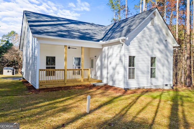 back of property with a yard, ceiling fan, and covered porch