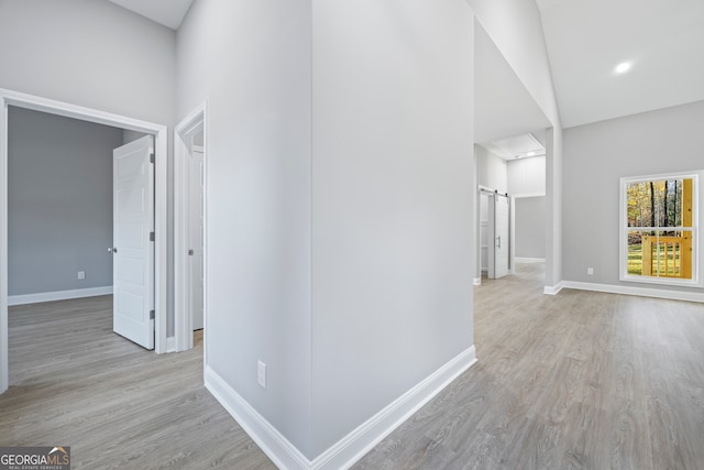 corridor with a barn door and light hardwood / wood-style floors