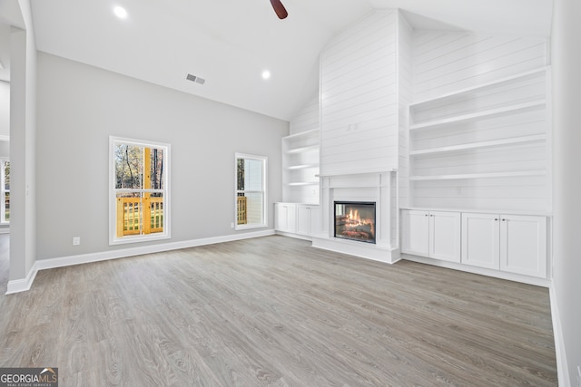 unfurnished living room featuring ceiling fan, a fireplace, light hardwood / wood-style floors, and high vaulted ceiling