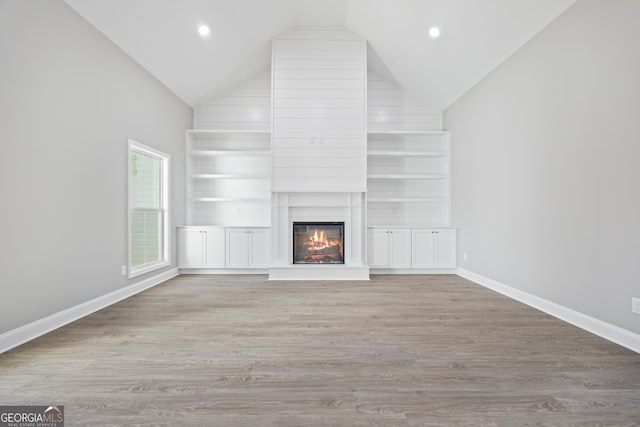 unfurnished living room featuring a large fireplace, high vaulted ceiling, and light hardwood / wood-style flooring