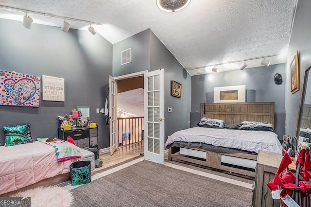 bedroom with lofted ceiling, rail lighting, and a textured ceiling