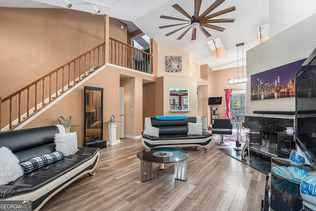 living room with high vaulted ceiling, track lighting, and hardwood / wood-style flooring