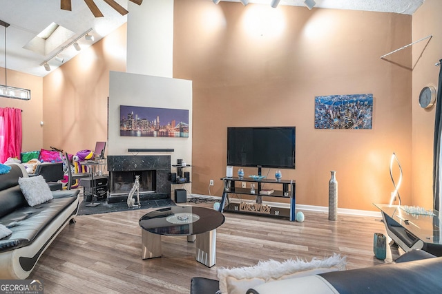 living room with a premium fireplace, ceiling fan, and wood-type flooring