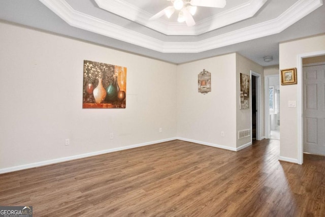 unfurnished room featuring a tray ceiling, crown molding, ceiling fan, and dark wood-type flooring