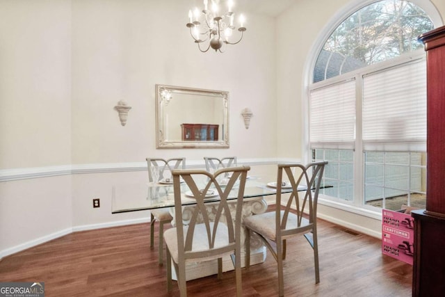 dining area with dark hardwood / wood-style floors and an inviting chandelier