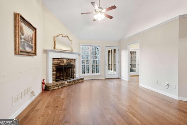 unfurnished living room featuring light hardwood / wood-style flooring, ceiling fan, and a stone fireplace