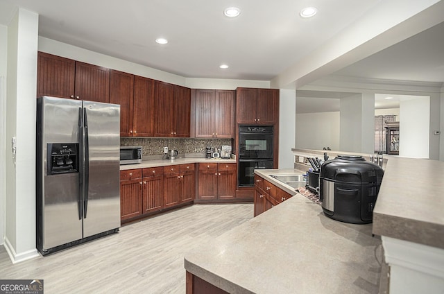 kitchen featuring backsplash, sink, stainless steel appliances, and light hardwood / wood-style flooring