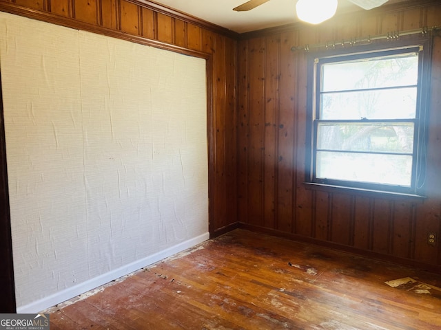 spare room featuring ceiling fan, dark wood-type flooring, and wood walls