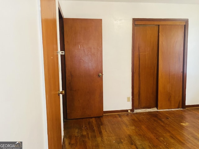 unfurnished bedroom featuring dark wood-type flooring and a closet