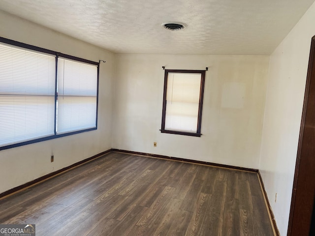 spare room featuring dark hardwood / wood-style flooring and a textured ceiling