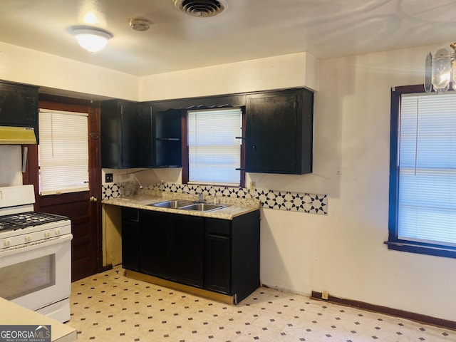 kitchen featuring white gas stove, sink, and exhaust hood