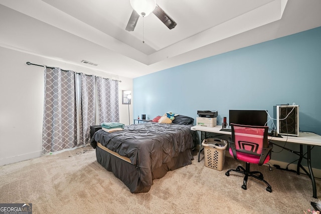 carpeted bedroom featuring ceiling fan and a raised ceiling