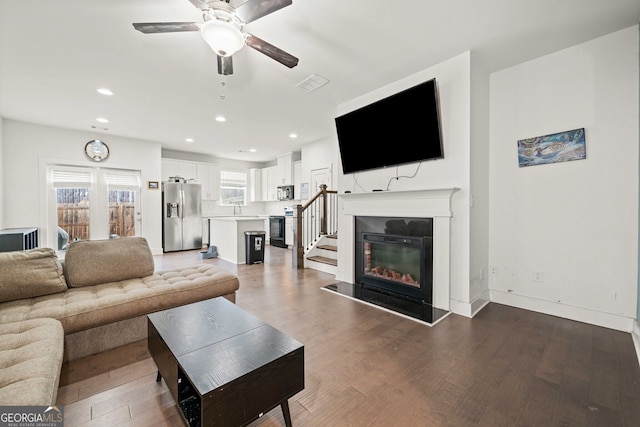 living room featuring ceiling fan, sink, and hardwood / wood-style flooring