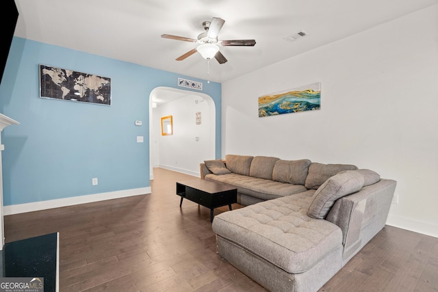 living room featuring ceiling fan and dark wood-type flooring