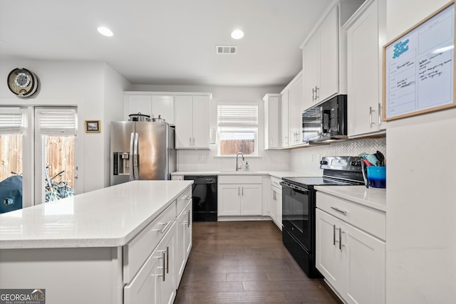 kitchen featuring dark hardwood / wood-style flooring, white cabinetry, a kitchen island, and black appliances