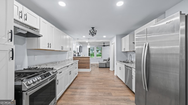 kitchen with light hardwood / wood-style floors, light stone counters, white cabinetry, and stainless steel appliances