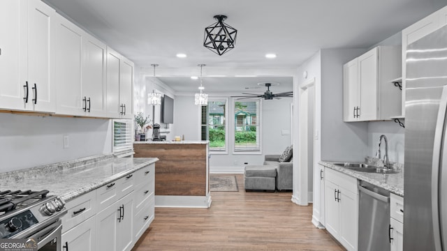 kitchen featuring sink, stainless steel appliances, pendant lighting, white cabinets, and light wood-type flooring