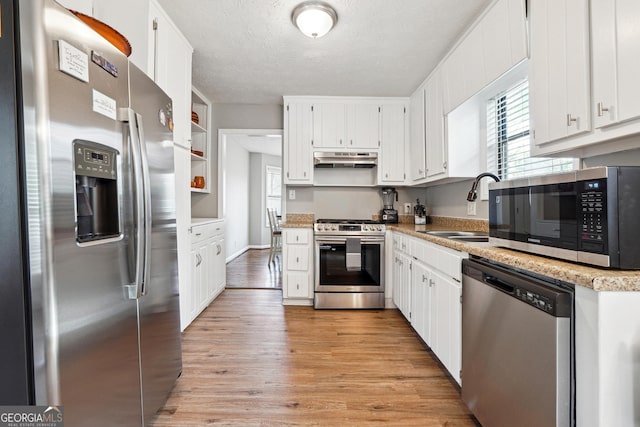 kitchen featuring sink, stainless steel appliances, light hardwood / wood-style floors, a textured ceiling, and white cabinets