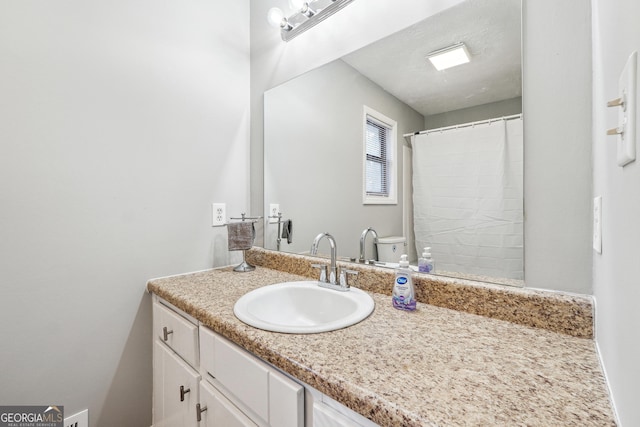 bathroom with a textured ceiling, vanity, toilet, and walk in shower