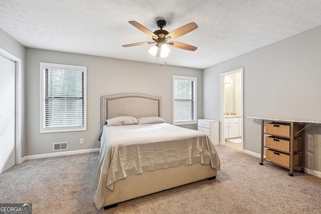 bedroom featuring a textured ceiling, connected bathroom, multiple windows, and ceiling fan