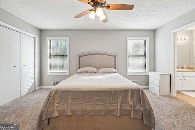 carpeted bedroom featuring ensuite bathroom, a closet, ceiling fan, and multiple windows