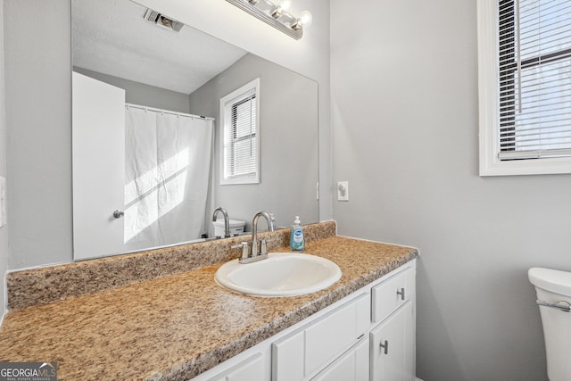 bathroom with vanity, toilet, and a textured ceiling