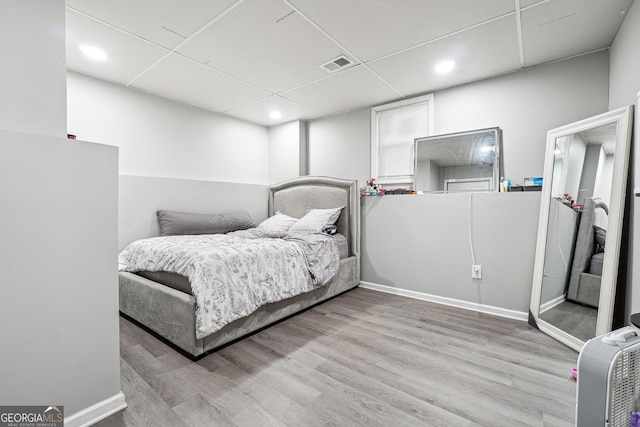 bedroom with a drop ceiling and light hardwood / wood-style floors