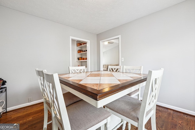 dining area with a textured ceiling and dark wood-type flooring