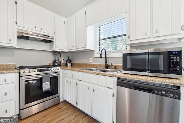 kitchen featuring a textured ceiling, stainless steel appliances, sink, light hardwood / wood-style floors, and white cabinetry