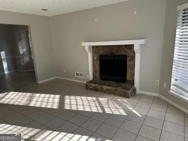 unfurnished living room with a fireplace, light tile patterned flooring, and a textured ceiling