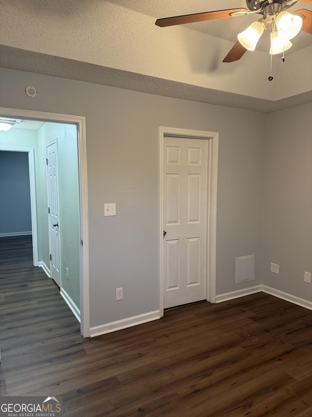 unfurnished room featuring a textured ceiling, dark hardwood / wood-style floors, and ceiling fan