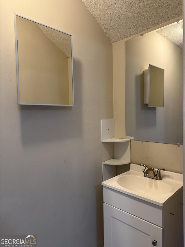 bathroom featuring vanity, a textured ceiling, and vaulted ceiling