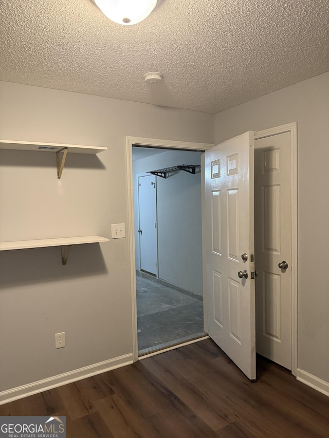 interior space with a textured ceiling and dark hardwood / wood-style floors