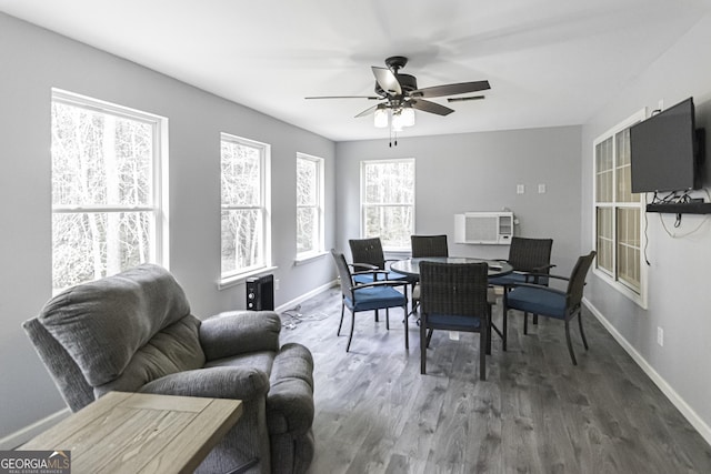 dining area with an AC wall unit, ceiling fan, and dark wood-type flooring