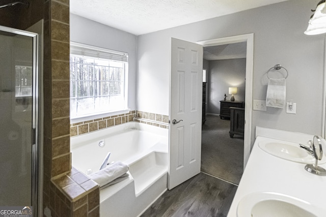 bathroom with hardwood / wood-style floors, vanity, separate shower and tub, and a textured ceiling