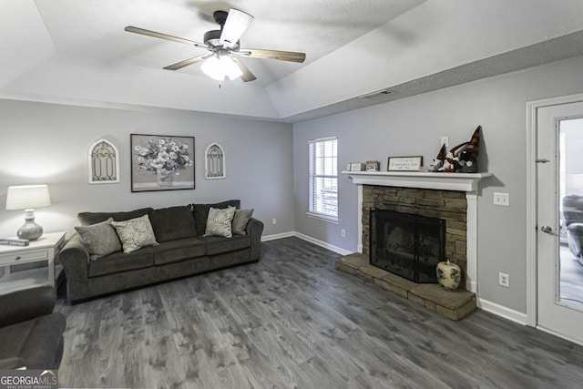 living room with a tray ceiling, ceiling fan, a fireplace, and dark hardwood / wood-style floors