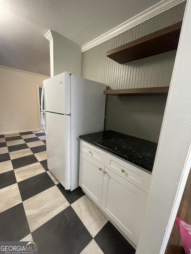 kitchen with white cabinetry, ornamental molding, a textured ceiling, and white refrigerator