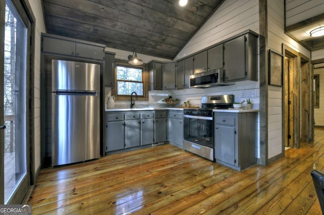 kitchen featuring appliances with stainless steel finishes, vaulted ceiling, sink, gray cabinets, and dark hardwood / wood-style floors