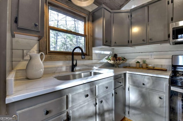 kitchen featuring gray cabinetry, backsplash, sink, and stainless steel appliances