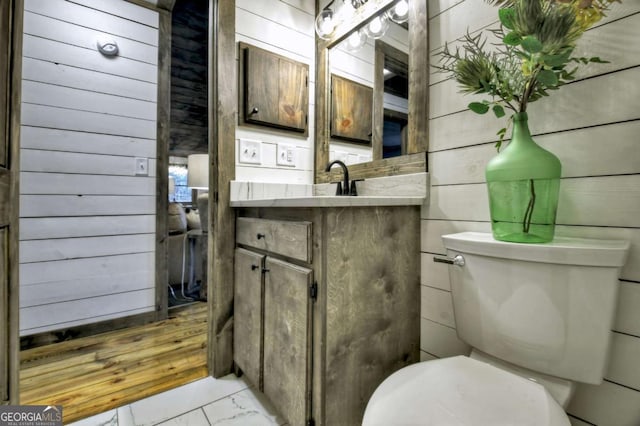 bathroom with vanity, toilet, wood-type flooring, and wooden walls