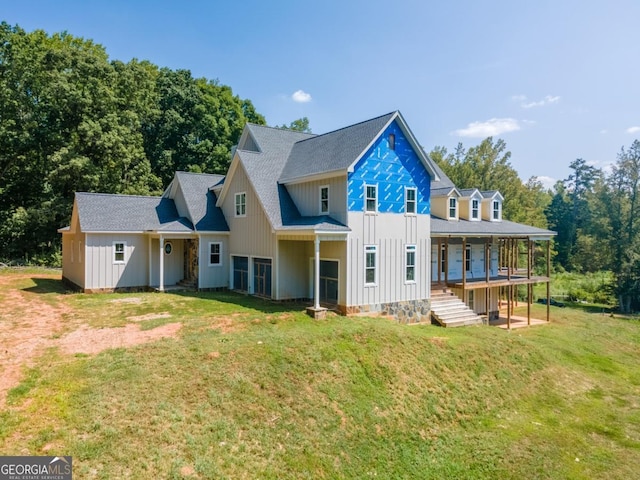 back of property with a porch, a yard, board and batten siding, and roof with shingles