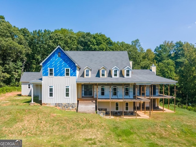 back of house with a patio, a yard, board and batten siding, and a chimney