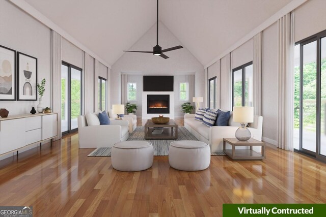 living area with a lit fireplace, high vaulted ceiling, a ceiling fan, and wood finished floors