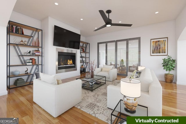 living room featuring recessed lighting, light wood-style floors, a warm lit fireplace, and a ceiling fan