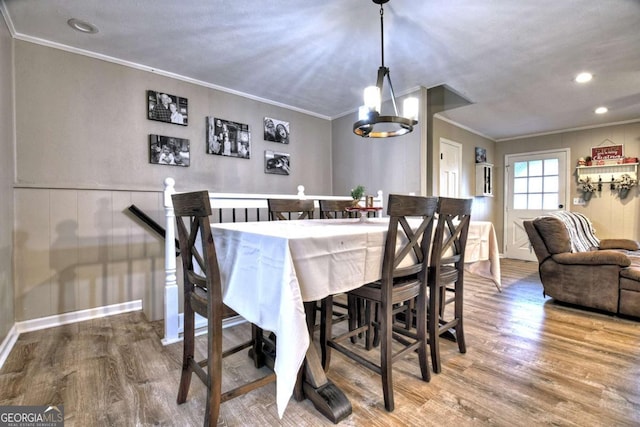 dining area featuring crown molding, an inviting chandelier, and hardwood / wood-style flooring