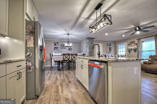 kitchen with pendant lighting, a kitchen island with sink, crown molding, light hardwood / wood-style flooring, and appliances with stainless steel finishes