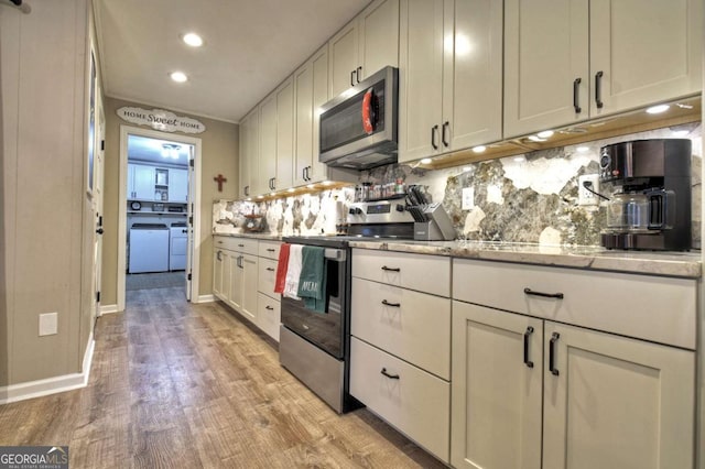 kitchen with tasteful backsplash, light hardwood / wood-style flooring, independent washer and dryer, white cabinets, and appliances with stainless steel finishes