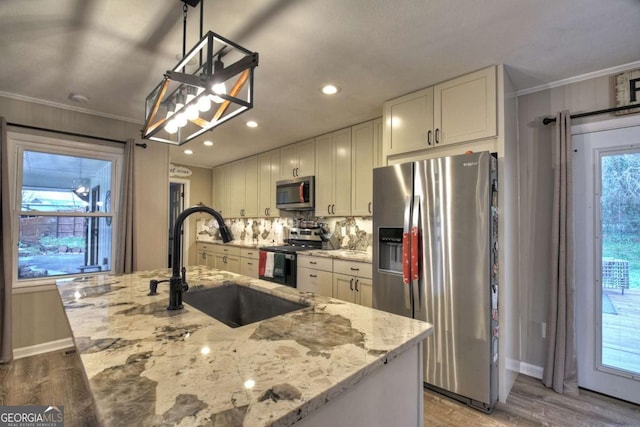 kitchen featuring light stone countertops, sink, hanging light fixtures, stainless steel appliances, and a center island with sink