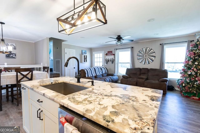 kitchen featuring light stone countertops, dark wood-type flooring, sink, white cabinets, and hanging light fixtures