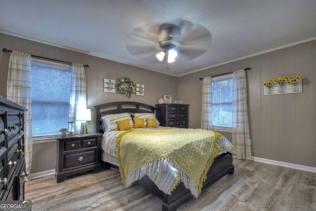 bedroom with multiple windows, ceiling fan, ornamental molding, and light wood-type flooring